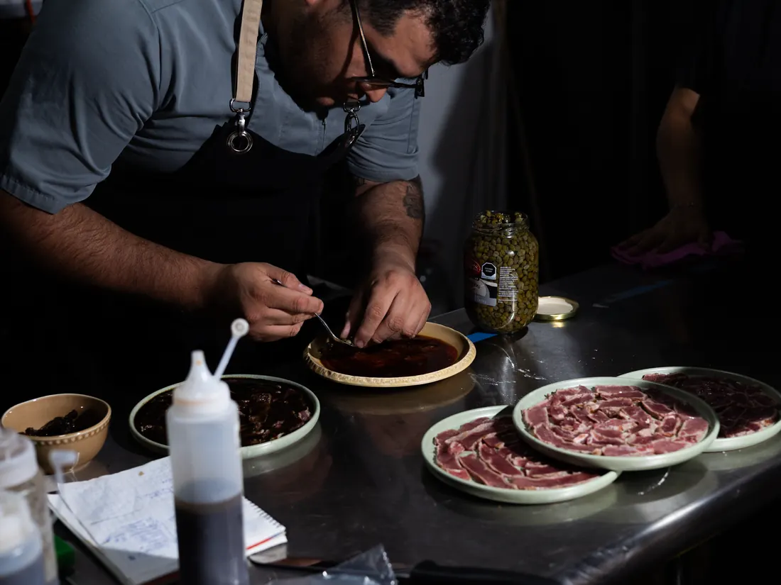 Cocinero emplatando carpaccios en la barra de Tierra y Comal