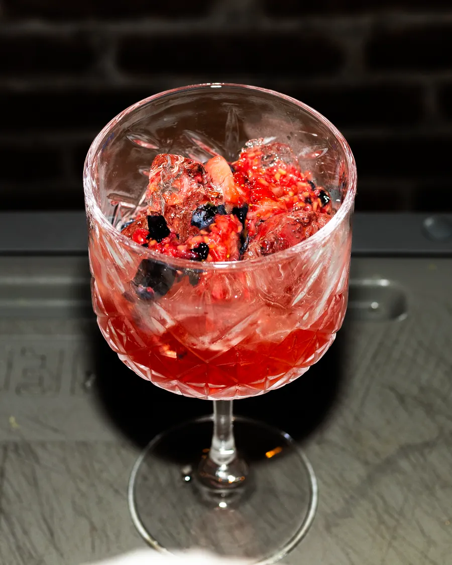 Coctel de frutos rojos servido en copa, en la barra de Tierra y Comal